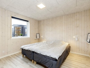 A bedroom with a bed, a window, and a wooden floor. - 5 Star Holiday Home in Vaeggerlose (Vaeggerlose)