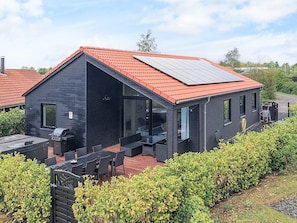 A modern house with a sloped roof, a patio with outdoor furniture, and a solar panel installation. - 5 Star Holiday Home in Vaeggerlose (Vaeggerlose)