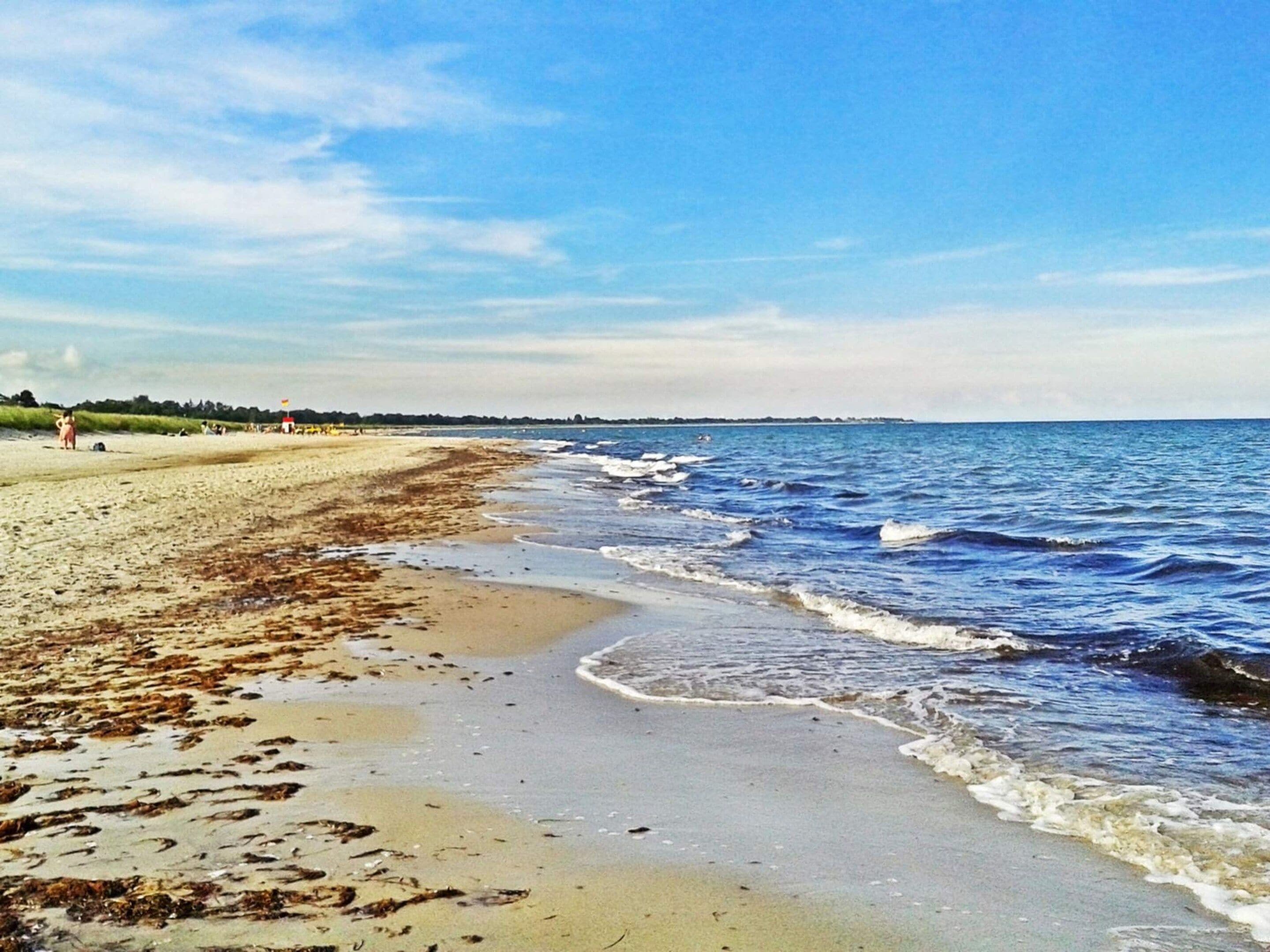 A beach with sand, waves, and a clear sky.