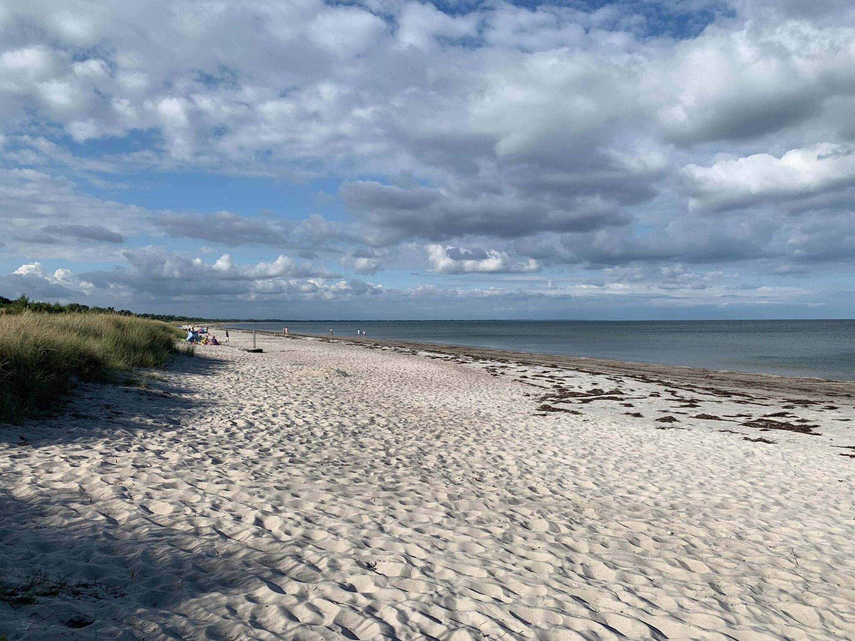 A sandy beach with a clear sky and distant horizon.