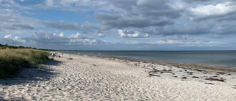 A sandy beach with a clear sky and distant horizon.