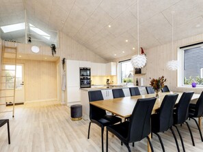 Une cuisine moderne dotée d’un îlot central, de planchers en bois et d’un coin repas avec une grande table et des chaises.