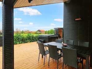 An outdoor patio with a wooden deck, a grill, and a table with chairs. - 5 Star Holiday Home in Vaeggerlose (Vaeggerlose)