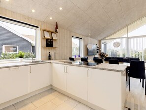 A modern kitchen with a large island, built-in appliances, and a dining area with black chairs. - 5 Star Holiday Home in Vaeggerlose (Vaeggerlose)