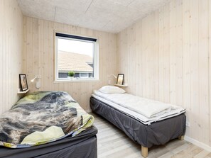 A bedroom with two beds, wooden walls, a window, and bedside lamps. - 5 Star Holiday Home in Vaeggerlose (Vaeggerlose)