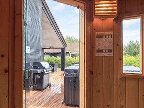 A wooden door leading to a deck with a barbecue grill and trash bins. - 5 Star Holiday Home in Vaeggerlose (Vaeggerlose)