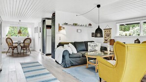 A modern living room with a sofa, yellow armchair, and a dining area with chairs. - 6 Person Holiday Home in Idestrup (Idestrup)