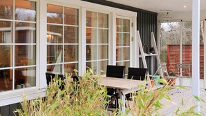 A covered outdoor area with a table and chairs, large windows, and a ladder. - 6 Person Holiday Home in Laeso (Læsø)