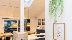 Una cocina moderna con un pilar de piedra, armarios oscuros y una planta colgante.