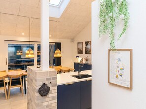 Una cucina moderna con un pilastro in pietra, mobili scuri e una pianta pensile.
