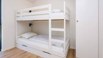 A bunk bed in a room with a wooden floor and a door on the right.