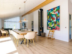 A spacious dining area with a long table and chairs, a fireplace, and a colorful abstract painting on the wall. - 5 Star Holiday Home in Albaek (Aalbaek)