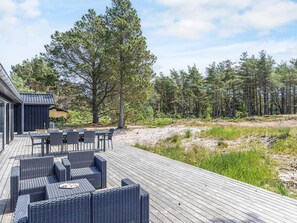 A wooden deck with outdoor furniture, surrounded by a forested area. - 5 Star Holiday Home in Albaek (Aalbaek)
