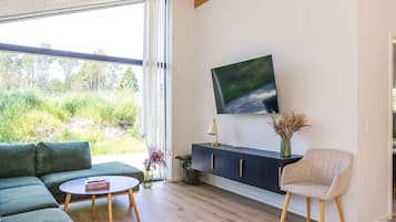 Un salon moderne comprenant un canapé, une table basse ronde, un meuble avec un téléviseur à écran plat et un fauteuil.