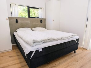 A bed with a grey headboard, white bedding, and a window with curtains. - 5 Star Holiday Home in Albaek (Aalbaek)