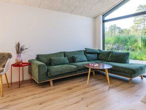 A modern living room with a green sectional sofa, a small red side table, and a round coffee table. - 5 Star Holiday Home in Albaek (Aalbaek)