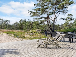 Ett trädäck med utemöbler, omgivet av ett skogsområde.