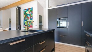 Una cocina moderna con encimera negra, electrodomésticos de acero inoxidable y suelo de madera.