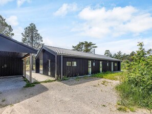 A modern building with a gravel driveway, wooden deck, and a metal roof. - 5 Star Holiday Home in Albaek (Aalbaek)