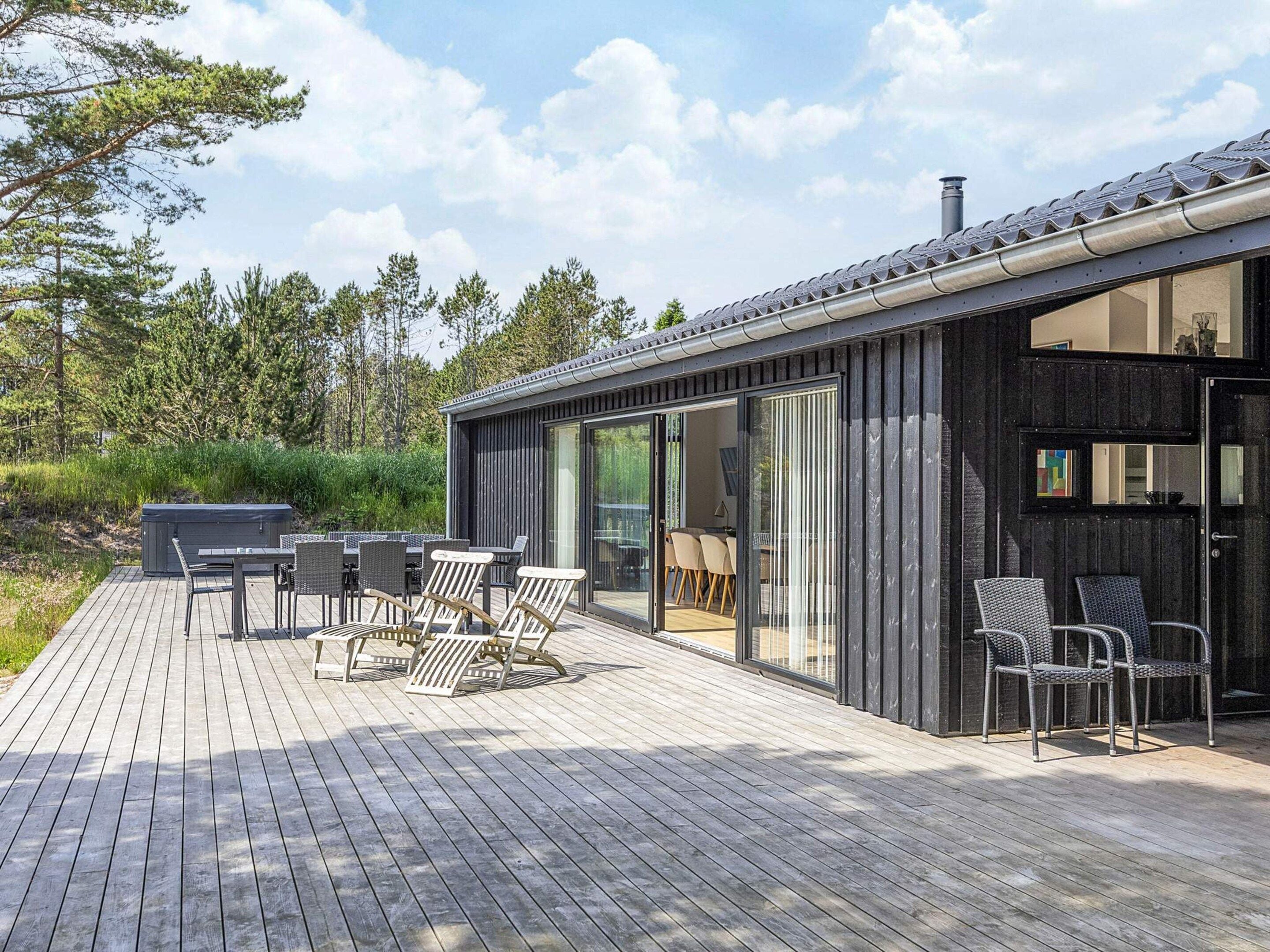 Eine moderne Außenterrasse mit Whirlpool, Essbereich und Sitzgelegenheiten.