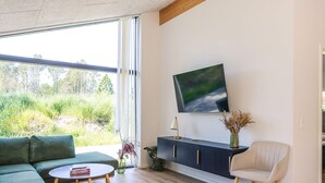 Una sala de estar moderna con un sofá, una mesa redonda de centro, un mueble aparador y un televisor montado en la pared.