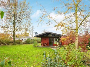 Une maison à l’extérieur rouge, avec une antenne parabolique et une pelouse.