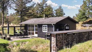 Een chalet met een terras, een stenen muur en uitzicht op het omliggende bos.