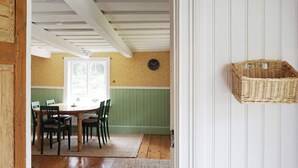 Un comedor con una mesa y sillas de madera, una pared verde y una cesta de mimbre en la pared.