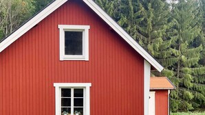 Un edificio rojo con techo a dos aguas y dos ventanas.