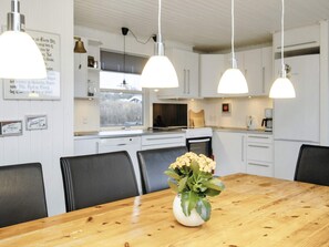 A modern kitchen with white cabinets, a wooden dining table, and three pendant lights. - 6 Person Holiday Home in Lokken (Lokken)