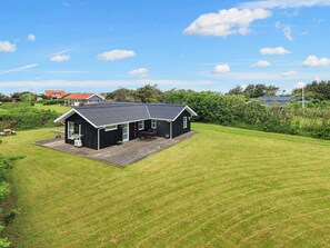 A black building with a sloped roof, a deck, and a grassy yard. - 6 Person Holiday Home in Lokken (Lokken)