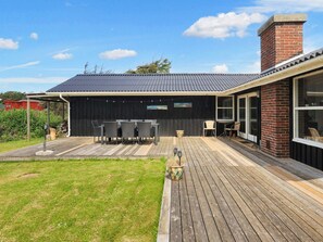 A house with a covered patio, a brick chimney, and a large window. - 6 Person Holiday Home in Lokken (Lokken)