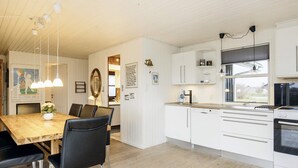 Eine moderne Küche mit weißen Schränken, einem Holztisch und schwarzen Stühlen.