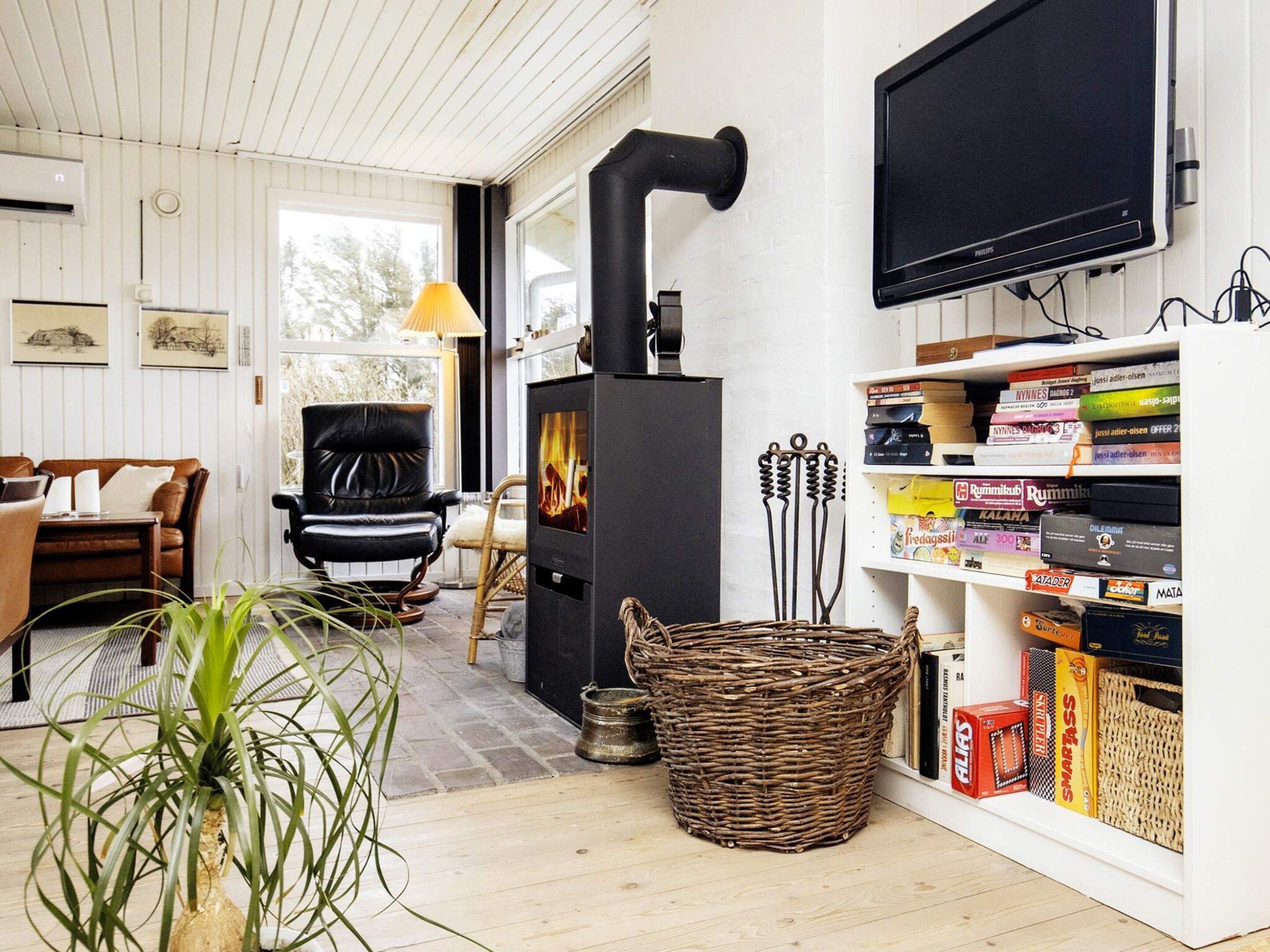 A cozy living room with a fireplace, comfortable seating, a television, and a bookshelf.