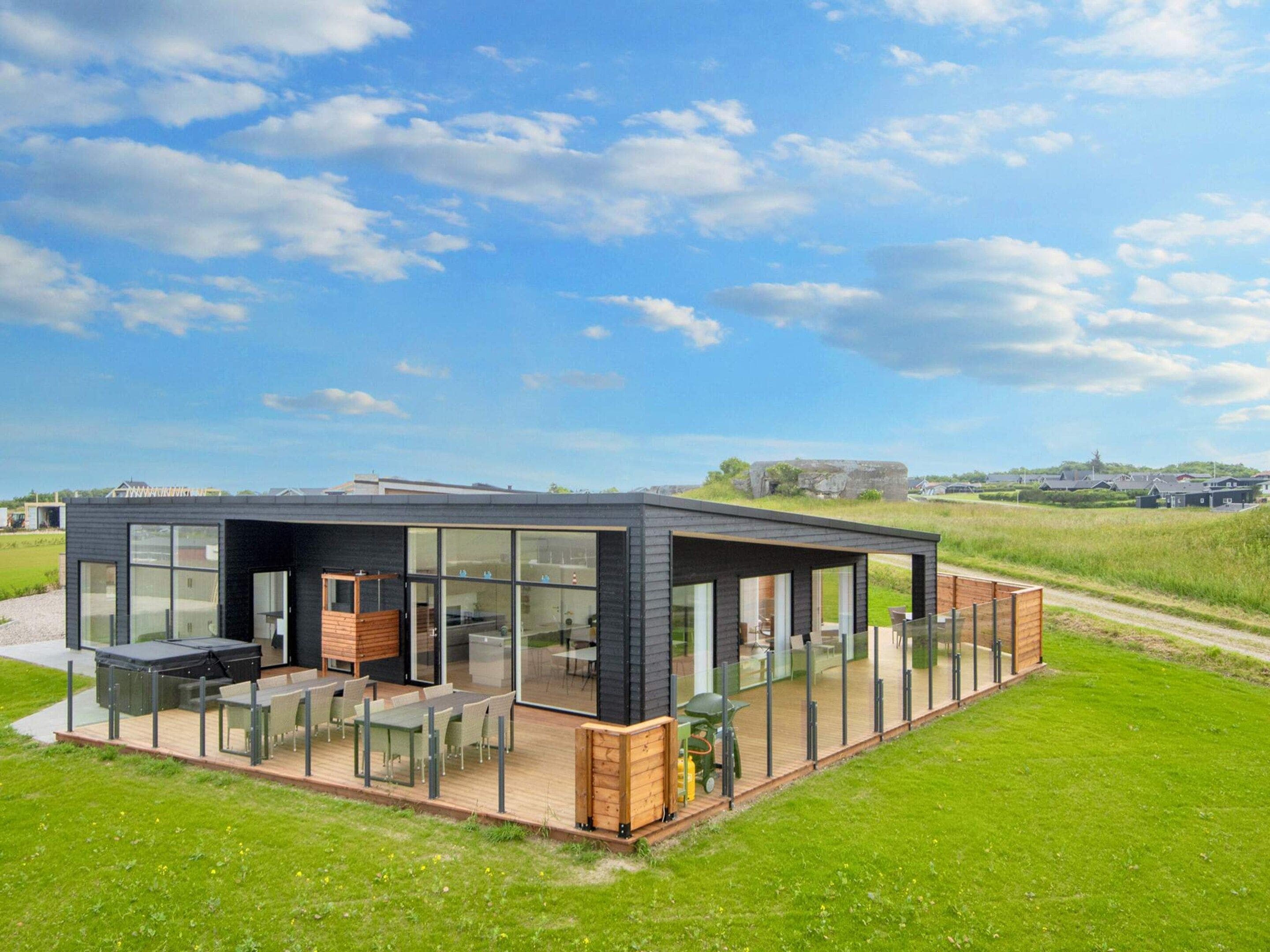 A modern, single-story building with a glass facade, an outdoor deck, and a patio area.