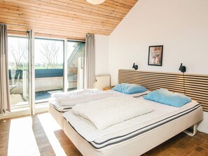 A bedroom with a large bed, a headboard with horizontal slats, a window with curtains, and a radiator. - 20 Person Holiday Home in Karby (Øster Assels)