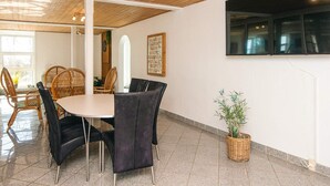 A dining area with a round table, black upholstered chairs, wooden ceiling, and a potted plant. - 20 Person Holiday Home in Karby (Øster Assels)