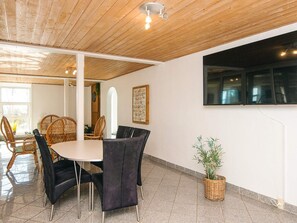 A dining area with a round table, black upholstered chairs, wooden ceiling, and a potted plant. - 20 Person Holiday Home in Karby (Øster Assels)