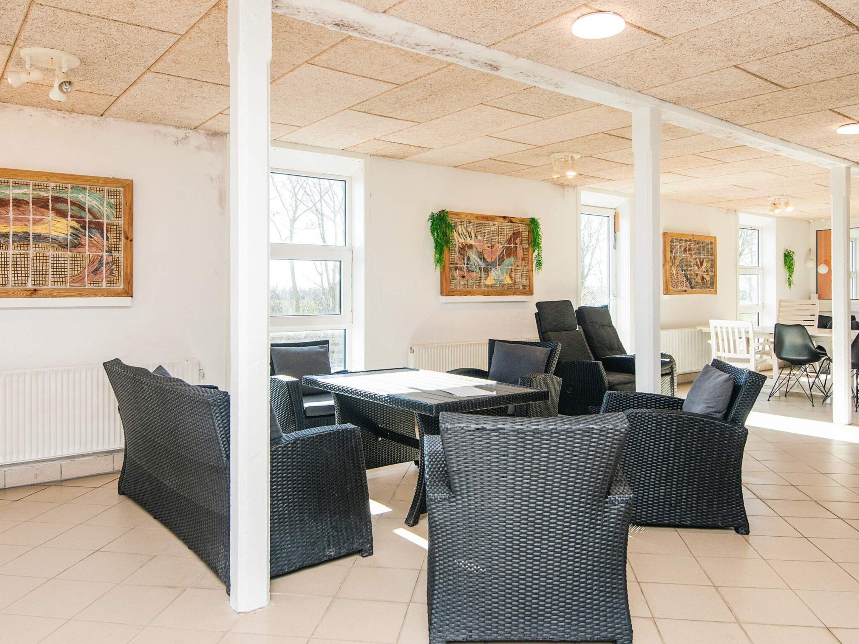 A spacious indoor area with a high ceiling, a central table with chairs, and artwork on the walls.
