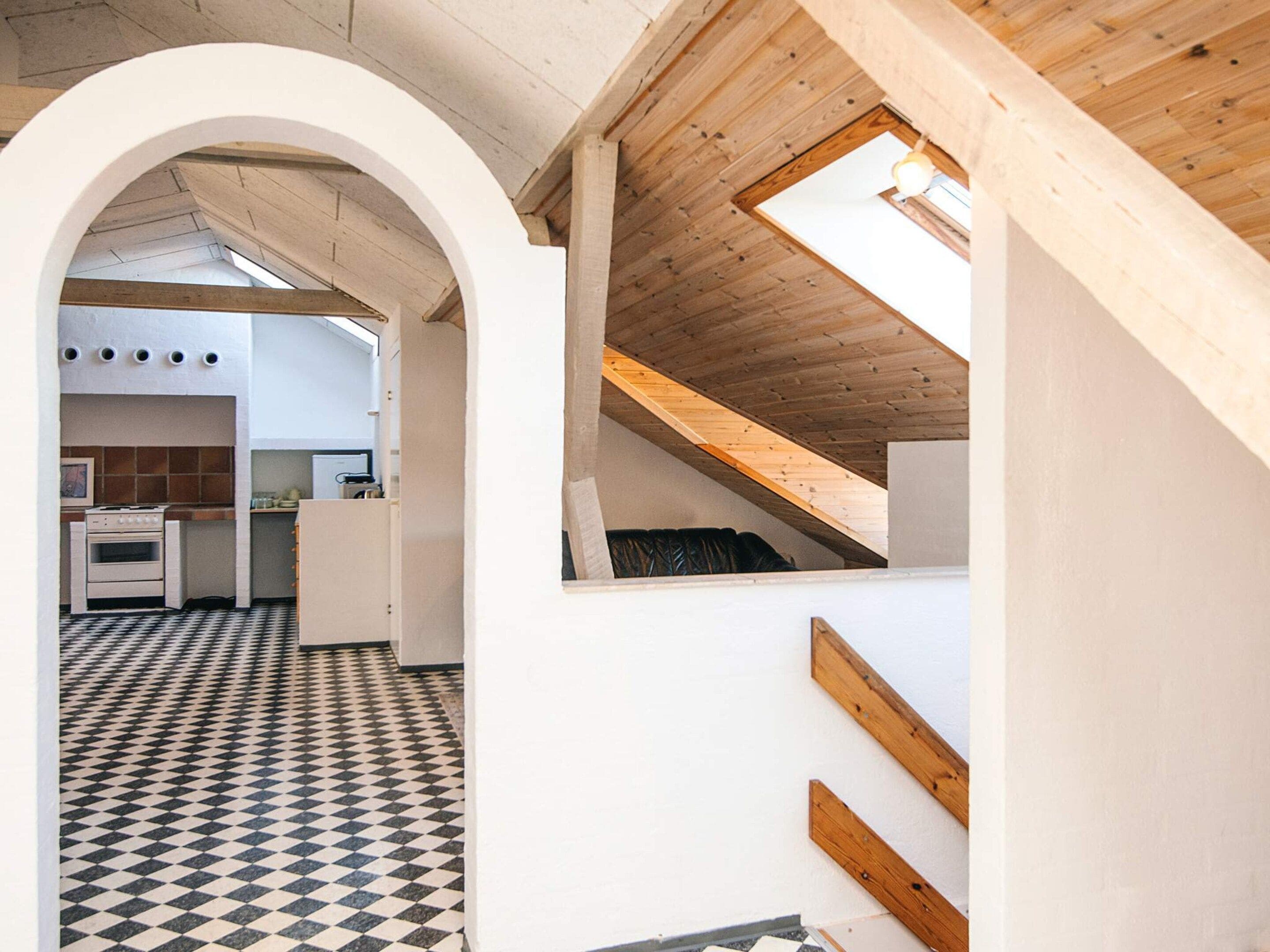 Une cuisine moderne avec un carrelage à motifs, une arche blanche et un plafond en pente doté d’une lucarne.