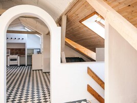 A modern kitchen with a checkered floor, a white archway, and a sloped ceiling with a skylight.