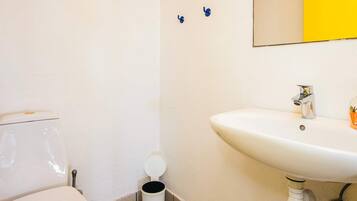 A bathroom with a toilet, a sink, and a trash bin.