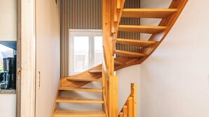 A wooden spiral staircase with a tiled floor leading to a door with vertical blinds. - 20 Person Holiday Home in Karby (Øster Assels)