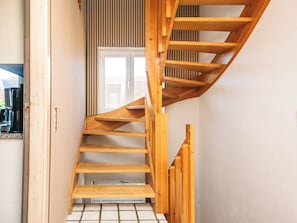 A wooden spiral staircase with a tiled floor leading to a door with vertical blinds. - 20 Person Holiday Home in Karby (Øster Assels)