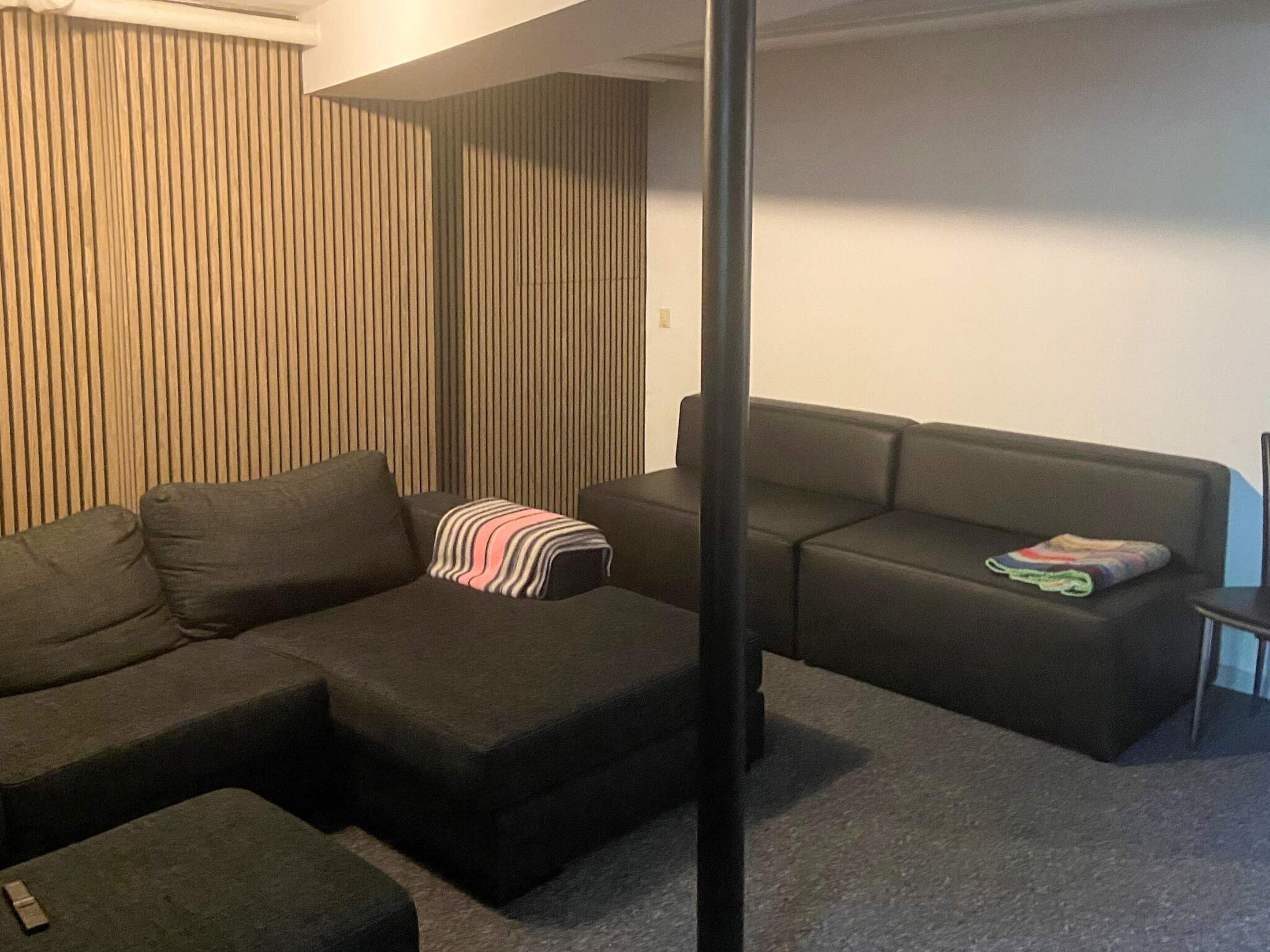 A modern living room with a sectional sofa, a small ottoman, and a striped throw blanket.