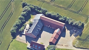 An aerial view of a building with a distinct L-shape, surrounded by green fields and trees. - 20 Person Holiday Home in Karby (Øster Assels)