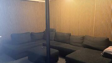 Una sala moderna con un sofá seccional, otomanas y un columnario alto y esbelto.