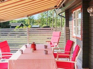 An outdoor patio with a striped tablecloth, red chairs, and a pitcher. - 4 Star Holiday Home in Ronneby (Listerby)