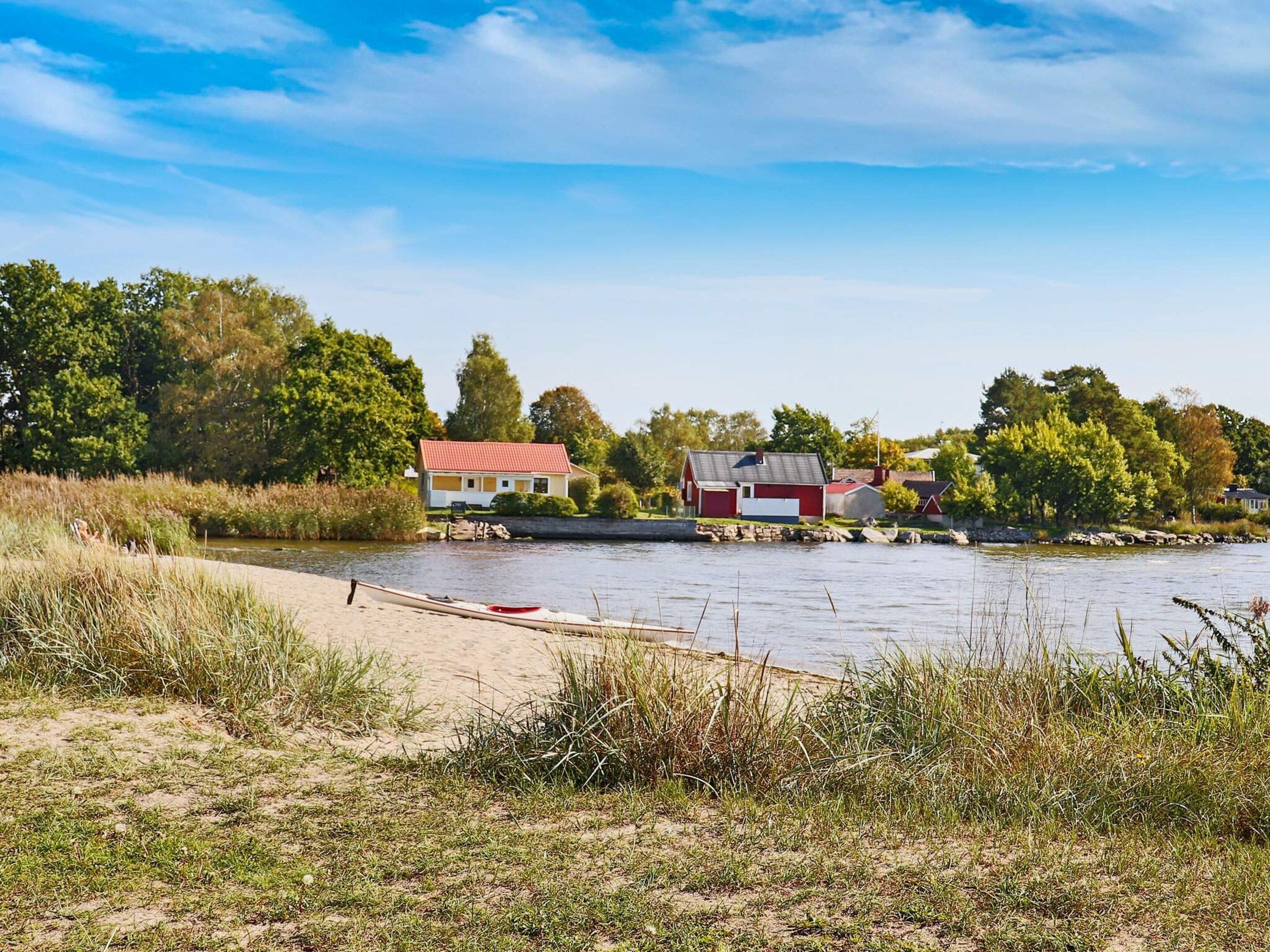 A riverside view with a small house and a red barn.