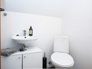 A small, white bathroom with a white sink, a bottle of hand soap, a toilet, and a towel on the counter. - 5 Person Holiday Home in Allingabro (Allingåbro)